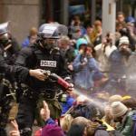 Gás lacrimogênio é lançado por policial da tropa de choque contra um grupo de manifestantes antiglobalização durante os confrontos em Seattle. Foto: Steve Kaiser.