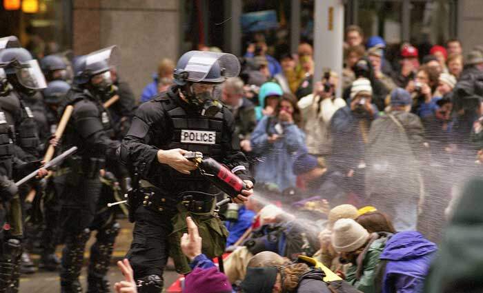 Gás lacrimogênio é lançado por policial da tropa de choque contra um grupo de manifestantes antiglobalização durante os confrontos em Seattle. Foto: Steve Kaiser.