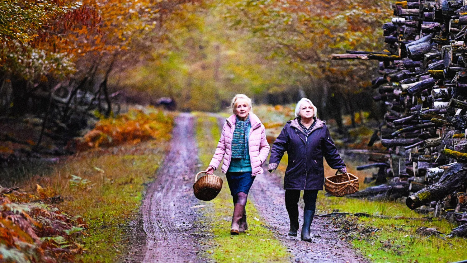 Cena de "Quando Chega o Outono" duas mulheres passeiam por uma área rural de mãos dadas.